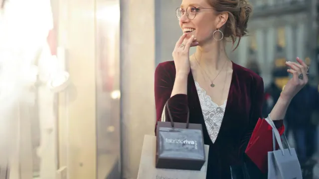 Woman looking into store window with shopping bags