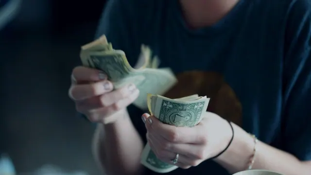 A person counting U.S. dollar bills