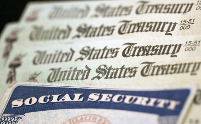 WASHINGTON, DC - OCTOBER 14: In this photo illustration, a Social Security card sits alongside checks from the U.S. Treasury on October 14, 2021 in Washington, DC. The Social Security Administration announced recipients will receive an annual cost of living adjustment of 5.9%, the largest increase since 1982. The larger increase is aimed at helping to offset rising inflation. (