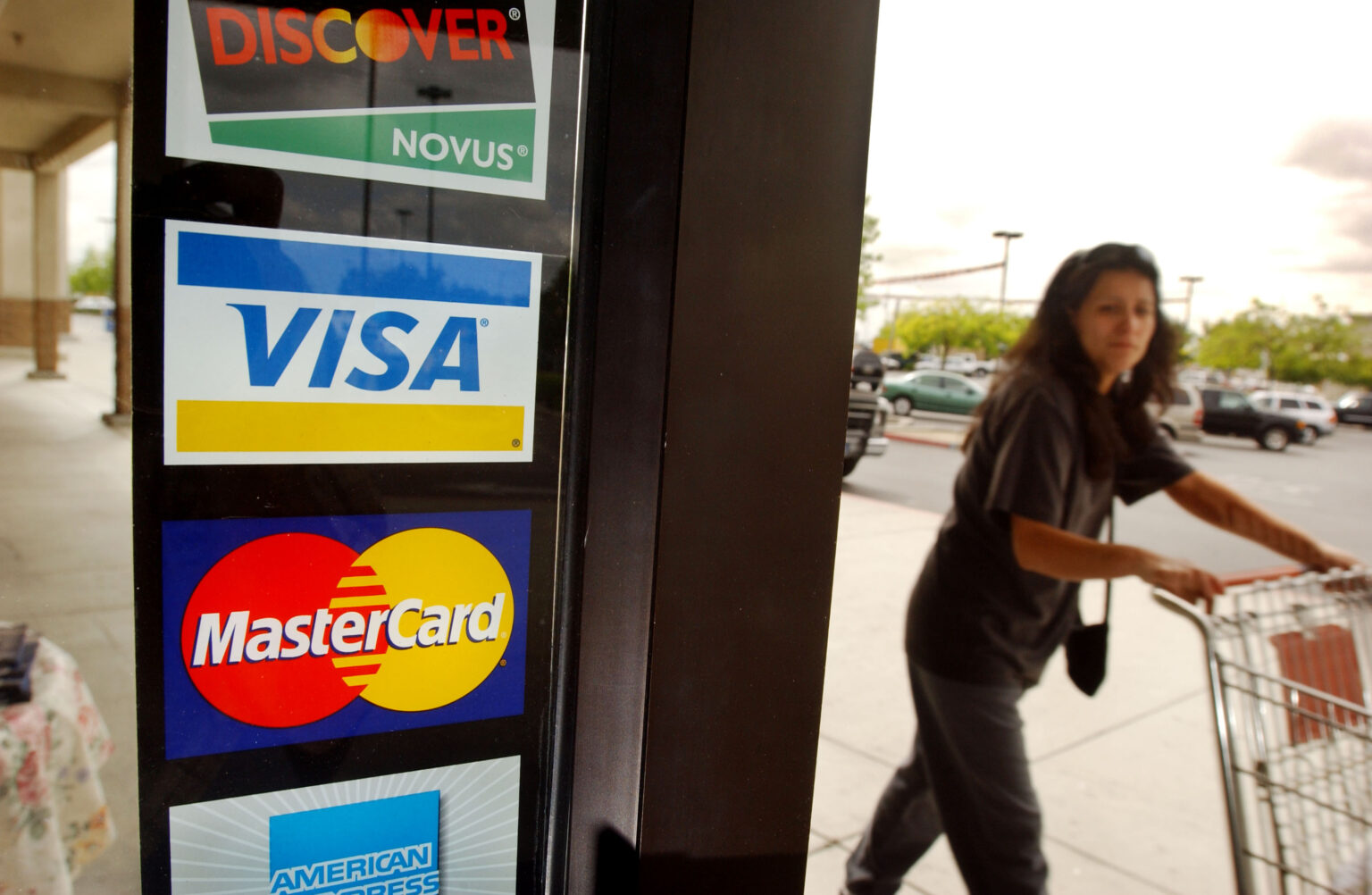 BAKERSFIELD, CA - APRIL 29: A shopper passes a shop door advertising acceptance of purchases with Master Card, Visa, and other credit cards April 29, 2003 in Bakersfield, California. MasterCard International made a surprise announcement April 28, moments before the start of trial, that it had struck a deal with U.S. retailers over the company's demand that stores accept their debit cards along with their credit cards, leaving Visa USA to battle with retailers including Sears, Wal-Mart, and Circuit City. Retailers claim that the credit card companies are not only forcing them to pay for the extra fees but are stifling competition.