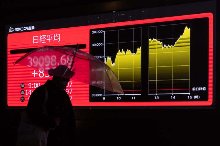 TOKYO, JAPAN - FEBRUARY 22: A pedestrian walks past an electronic board displaying the closing figure of the Nikkei Stock Average on February 22, 2024 in Tokyo, Japan. The Nikkei 225 stock index in Japan reached a historic milestone today, closing at a record high of 39,098.68 Japanese Yen marking a significant moment in the country's financial markets and surpassing its previous peak set over three decades ago.