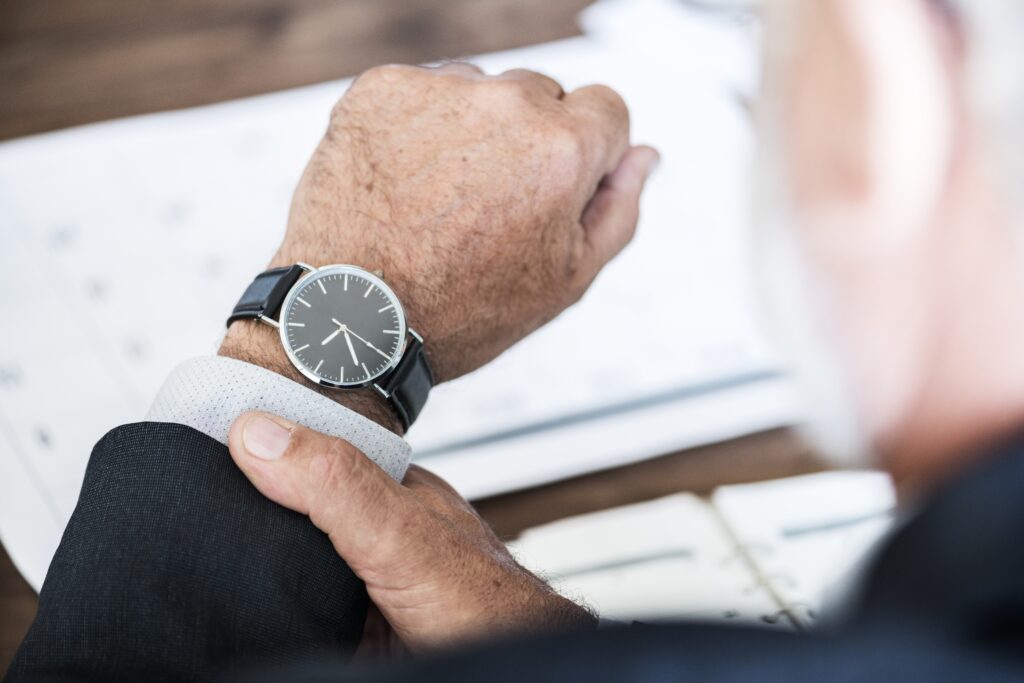 Over the shoulder view of a person looking at the time on his wrist watch as candidate is late, a worst interview behavior.