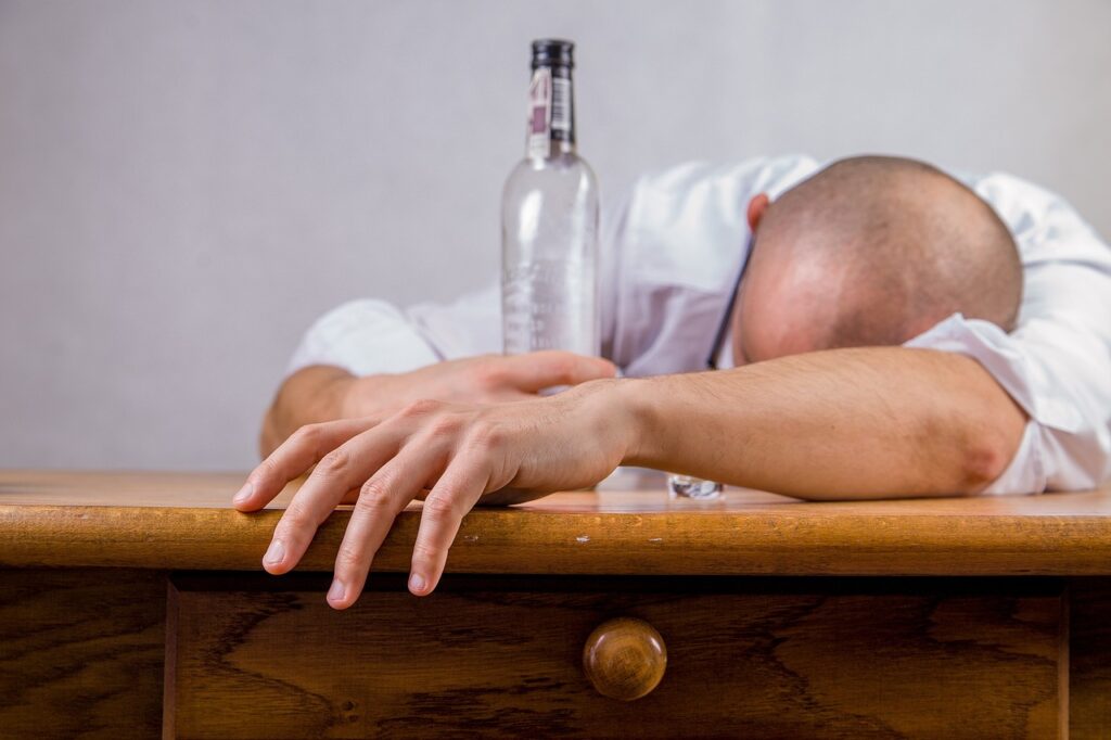 man slumped over a desk with a bottle of alcohol as a worst interview behavior