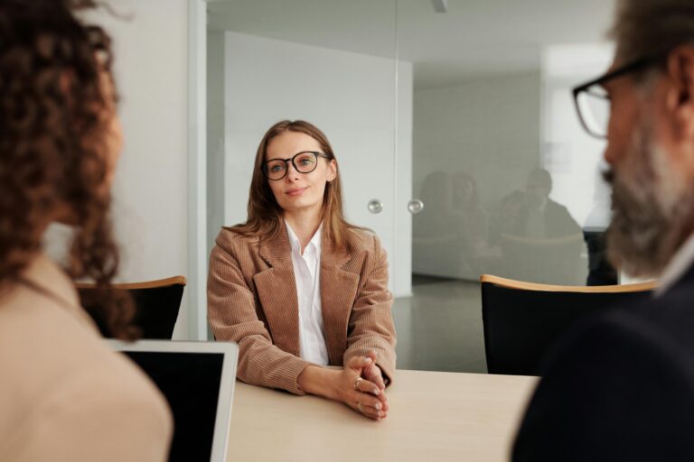 woman sits with two prospective employers in an office for a job interview