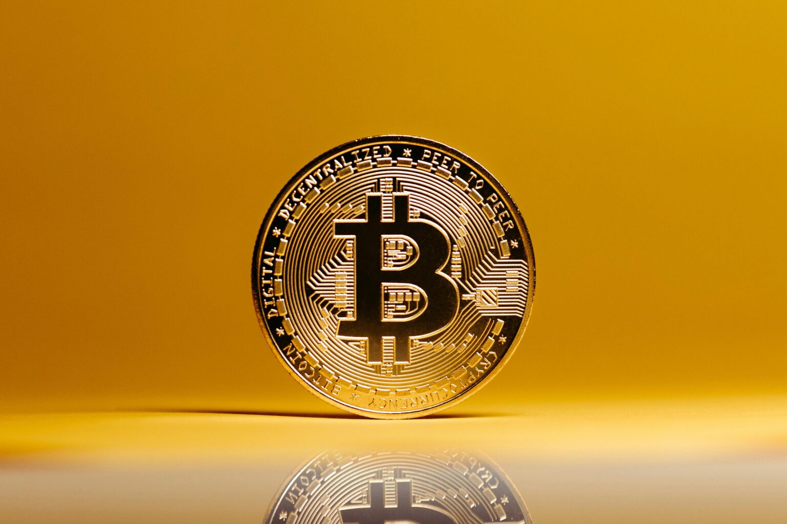 Photo of Bitcoin "coin" against a solid yellow background