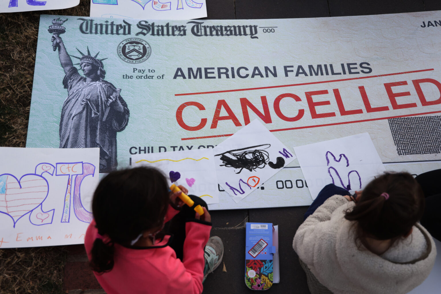 WASHINGTON, DC - DECEMBER 13: Children draw on top of a 'cancelled check' prop during a rally in front of the U.S. Capitol December 13, 2021 in Washington, DC. ParentsTogether Action held a rally with parents, caregivers and children to urge passage of the Build Back Better legislation to extend the expanded Child Tax Credit that will expire on January 15, 2022.