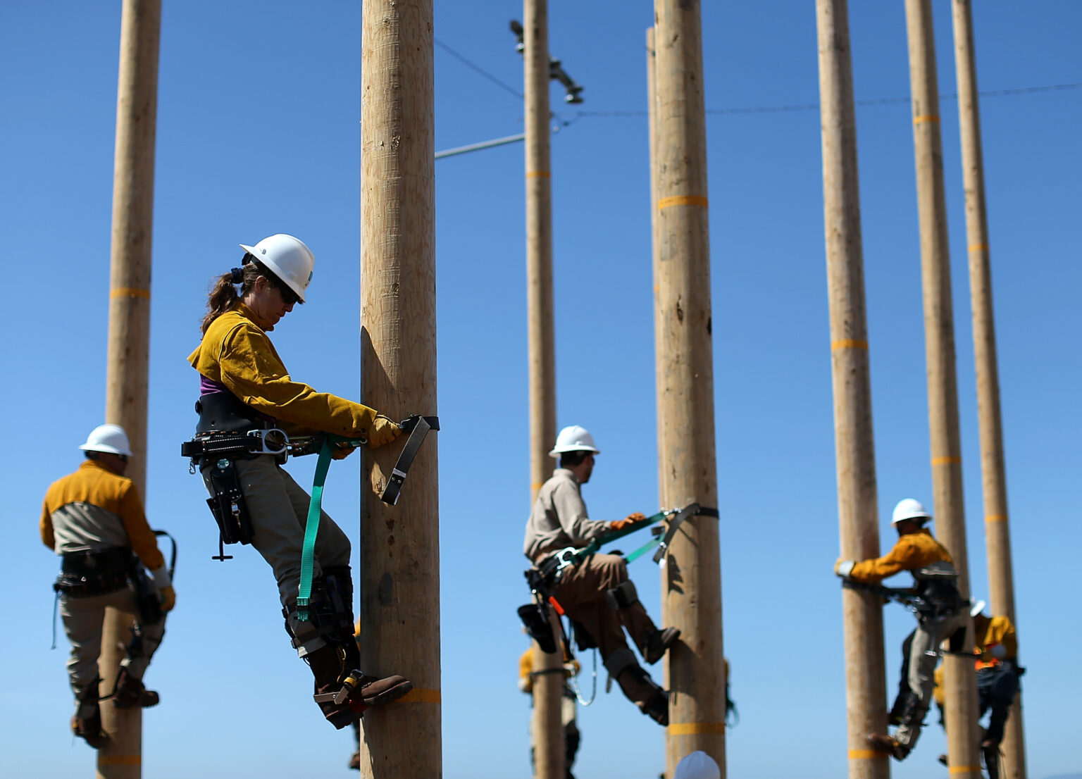 OAKLAND, CA - JUNE 08: Students participating in Pacific Gas and Electric's (PG&E) PowerPathway Pole Climbing Capstone course climb utility poles at the PG&E pole climbing training facility on June 8, 2012 in Oakland, California. Students who are aspiring utility workers from Oakland's Cypress Mandela Training Center and Workforce Institute, a Division of San Jose/Evergreen Community College District, are participating in PG&E's PowerPathway program Pole Climbing Capstone course, a three week course that teaches skills to better prepare individuals to compete for jobs such as pre-apprentice lineworker within the utility industry. The free course is held at the new pole climbing training facility at PG&E's Oakport Service Center.