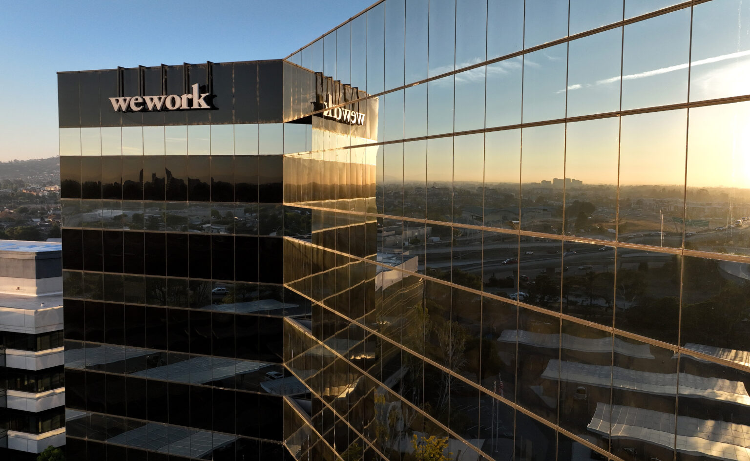 SAN MATEO, CALIFORNIA - NOVEMBER 01: In an aerial view, a sign is posted on the exterior of a WeWork office on November 01, 2023 in San Mateo, California. Shares of WeWork dropped over 35 percent in Wednesday morning trading following news reports that the New York-based company is planning to file for Chapter 11 bankruptcy.