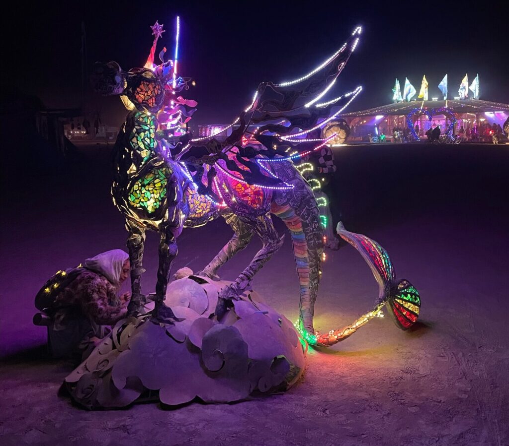 lit up unicorn rainbow art installation at 2024 burning man festival in black rock city nevada