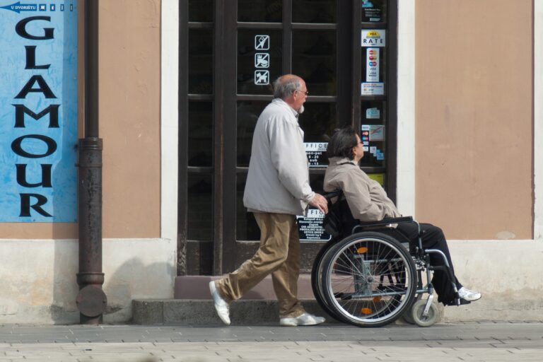 man pushes elderly woman in wheelchair