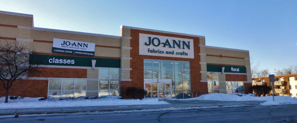 storefront of Joann's Fabrics against a blue sky with snow out front. 