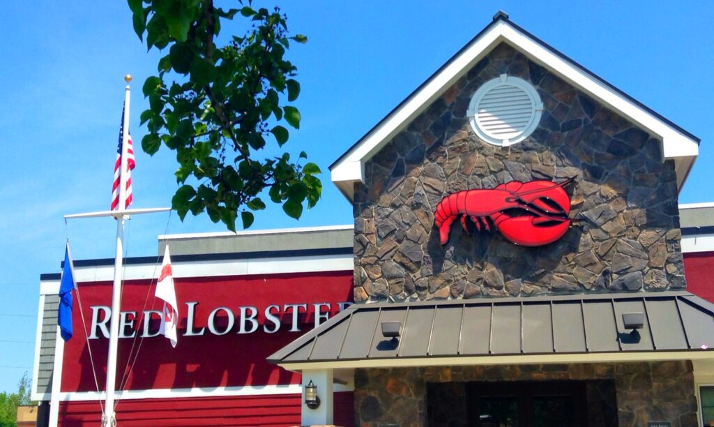 Storefront of a Red Lobster location with an American flag against a blue sky