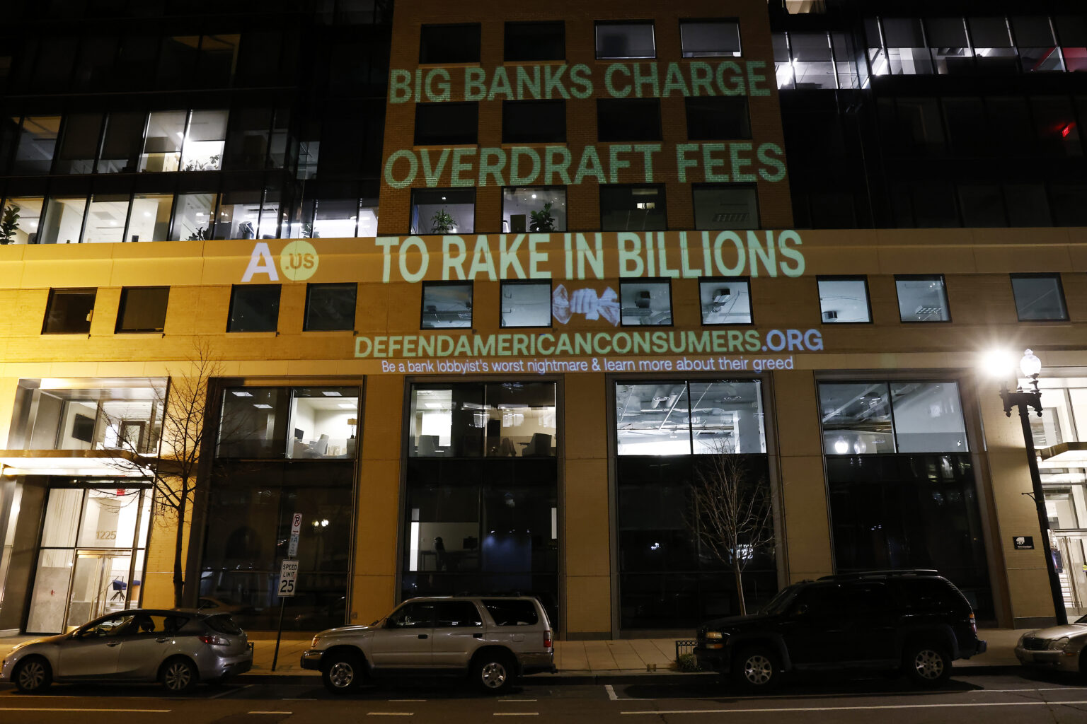 WASHINGTON, DC - FEBRUARY 06: Government Watchdog Accountable.US projects a graphic onto the Consumer Bankers Association HQ to highlight alleged big bank profiteering via overdraft junk fees in on February 06, 2024 in Washington, DC.