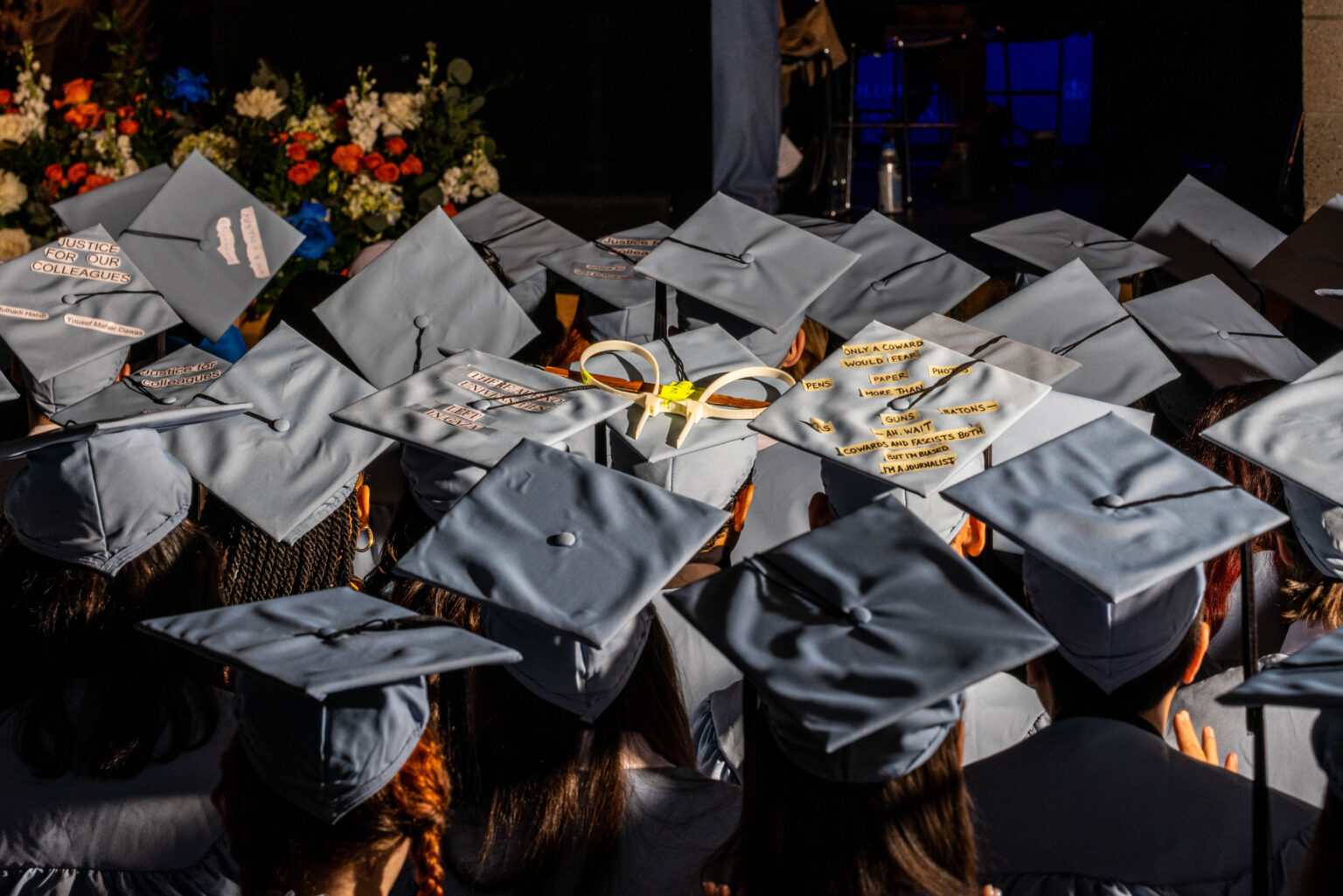 NEW YORK, NEW YORK - MAY 15: Edward Lopez's cap, decorated with zip-ties and a piece of the broken Hamilton Hall door from the night students barricaded themselves inside the building, is seen among fellow graduates during Columbia University's Journalism School accept diplomas on May 15, 2024 in New York City. Police arrested nearly 100 people as they cleared Columbia University of pro-Palestinian demonstrators who were issued a notice to disband an encampment after negotiations failed to come to a resolution.