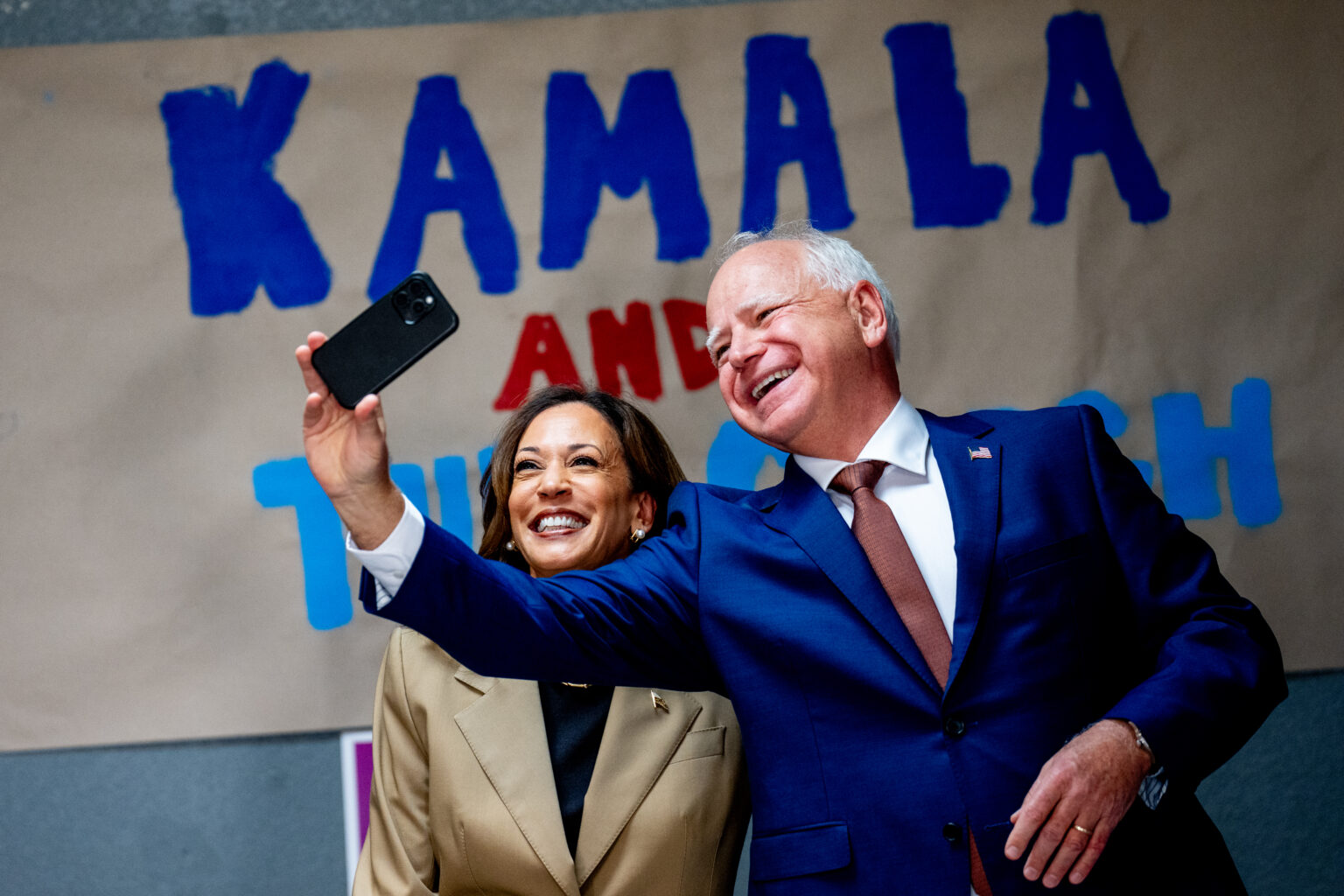 GLENDALE, ARIZONA - AUGUST 9: Democratic presidential candidate, U.S. Vice President Kamala Harris and Democratic vice presidential candidate Minnesota Governor Tim Walz take a selfie in front of a sign that reads "Kamala and The Coach" during stop at a campaign office on August 9, 2024 in Glendale, Arizona. Kamala Harris and her newly selected running mate Tim Walz are campaigning across the country this week. The Harris-Walz policies involve taxing the wealthy and boosting the middle class.