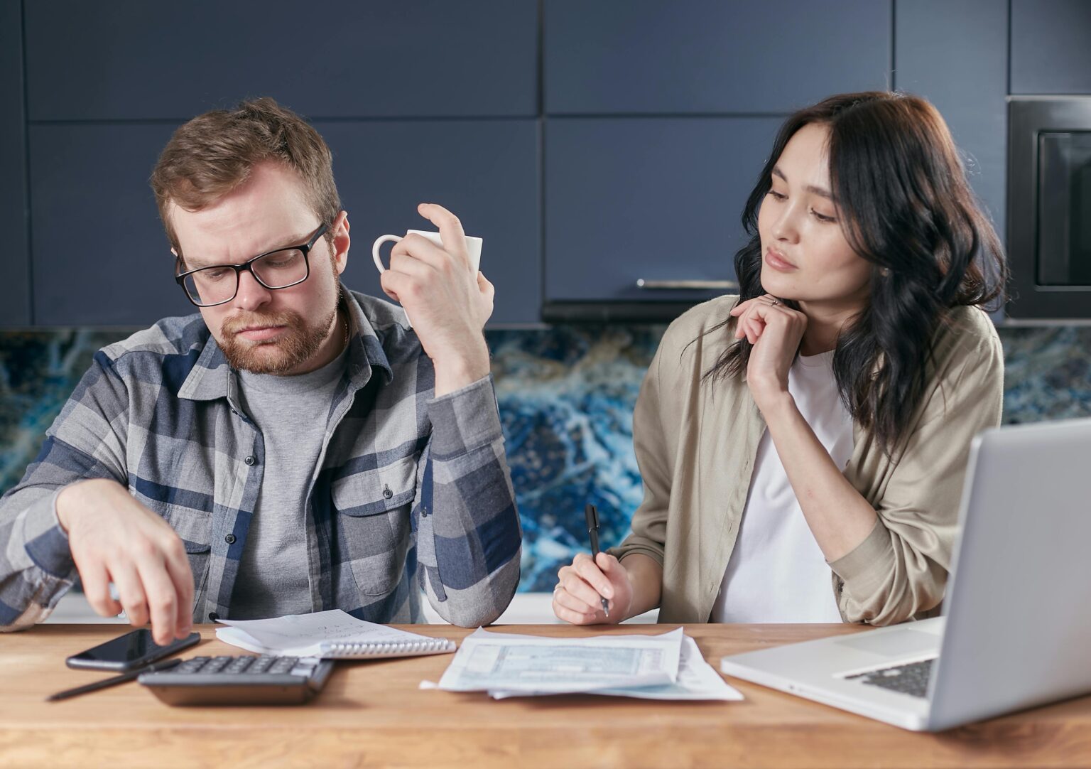 man and woman sit at a desk with bills on it