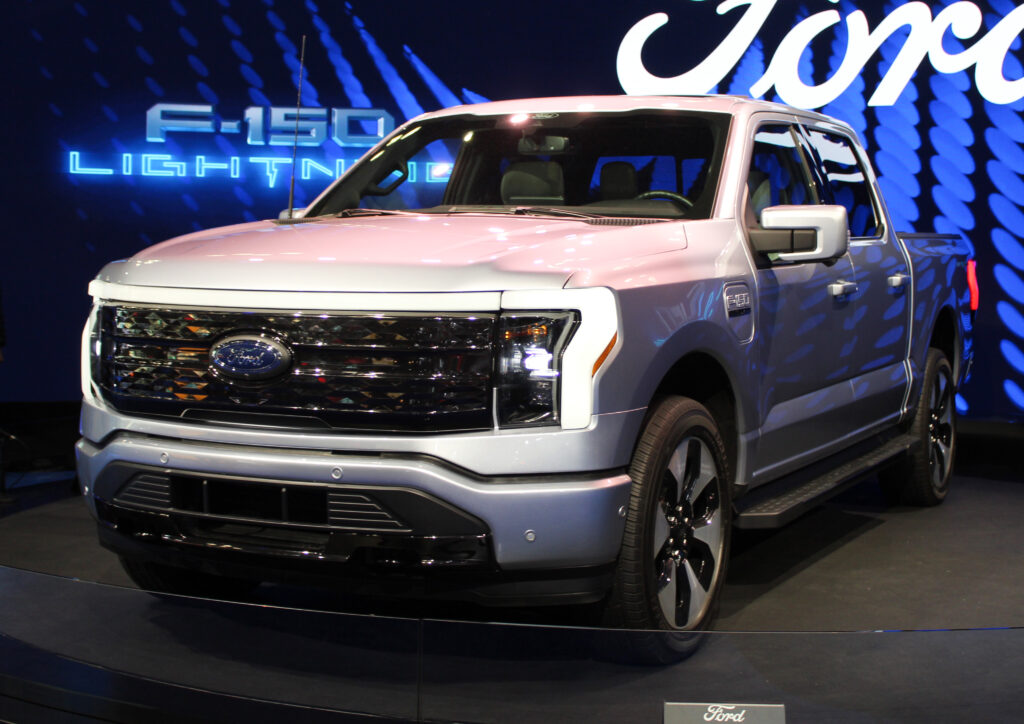 A silver 2022 Ford F-150 lighting pick up truck in a show room. 