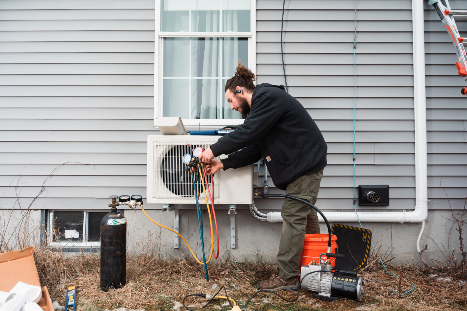 WINDHAM, ME - JANUARY 19: Matt Johnson, 38, an HVAC technician with ReVision Energy, a New England company specializing in solar energy and electric heat pump installations, works on removing all moisture from the line set of an newly installed electric heat pump on a home in Windham, Maine on Thursday, January 19, 2023. Improved energy efficiency with heat pump technology and new tax incentives have contributed to the popularity of heat pumps in New England, as many homeowners are facing increased costs of heating their homes with oil, propane and other fossil fuels.