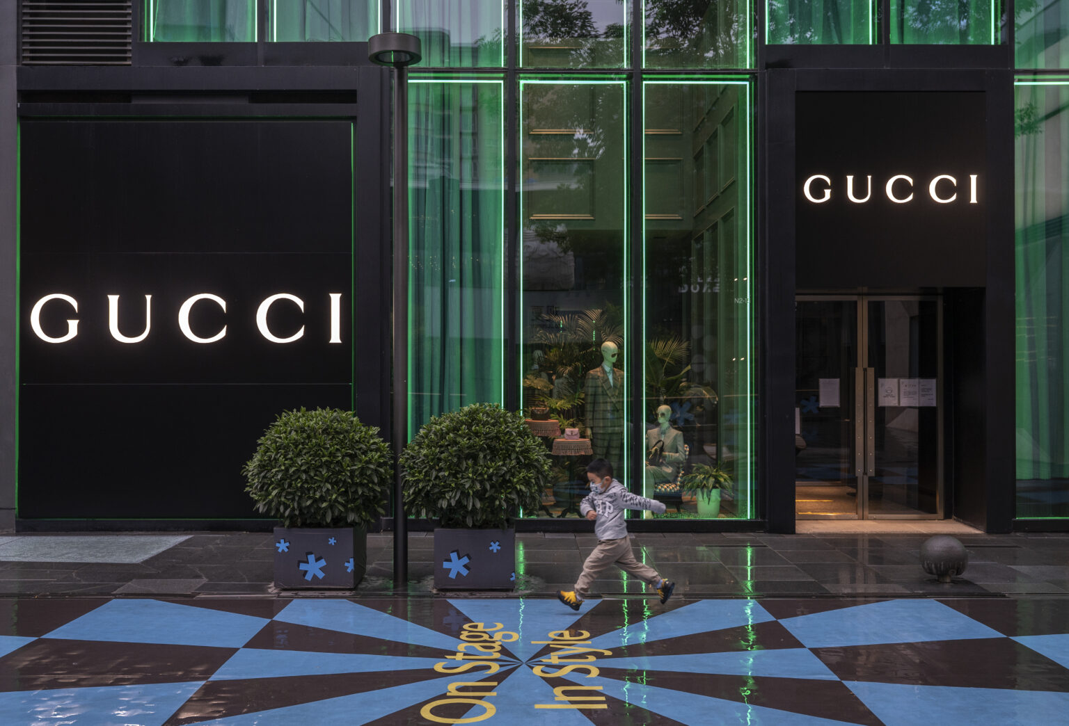 BEIJING, CHINA - MAY 10: A boy runs by a closed store of the luxury brand Gucci at Taikoo Li mall in Sanlitun after many retail stores were closed to help prevent the spread of COVID-19 on May 10, 2022 in Beijing, China. China is trying to contain a spike in coronavirus cases in the capital Beijing after hundreds of people tested positive for the virus in recent weeks, causing local authorities to initiate mass testing in most districts, close schools and stores, ban gatherings and inside dining in all restaurants, and to lockdown some neighbourhoods in an effort to maintain the country's zero COVID strategy.