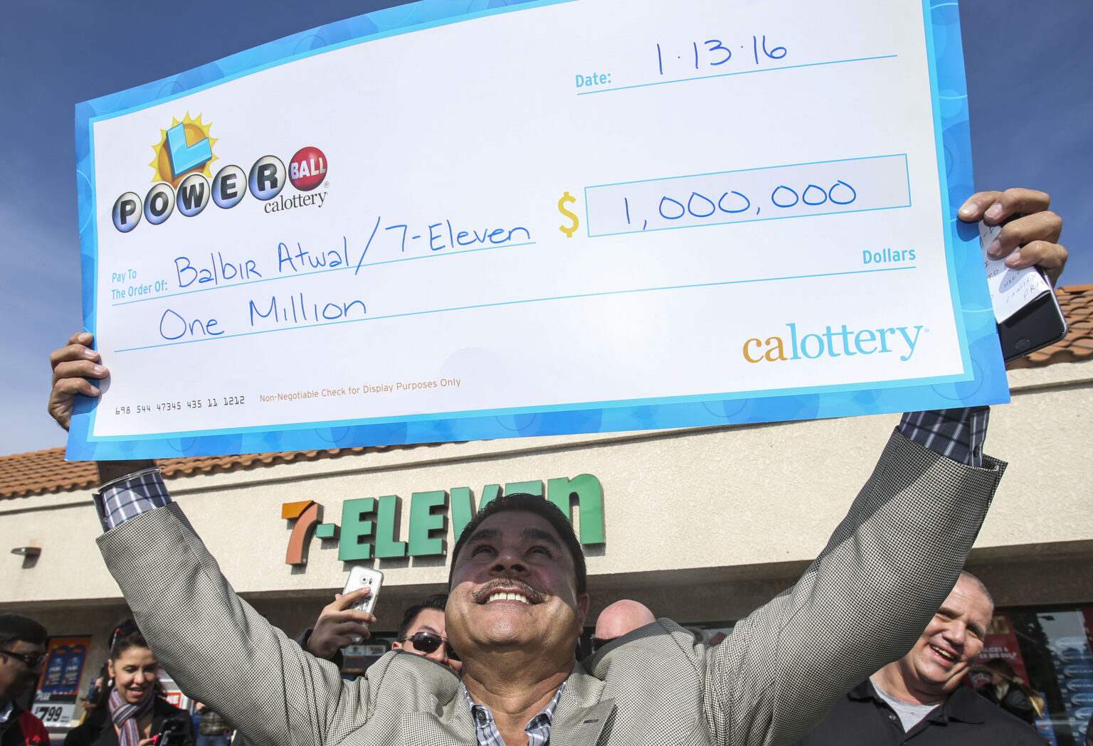 CHINO HILLS, CA - JANUARY 14: Balbir Atwal, owner of the California 7-Eleven that sold one of the 3 Powerball winning tickets, holds up a $1 million check after received from the California State Lottery, in front of his store on January 14, 2016 in Chino Hills, California. Winning tickets were also sold in Florida and Tennessee and will share an estimated record-breaking $1.58 billion dollar jackpot.