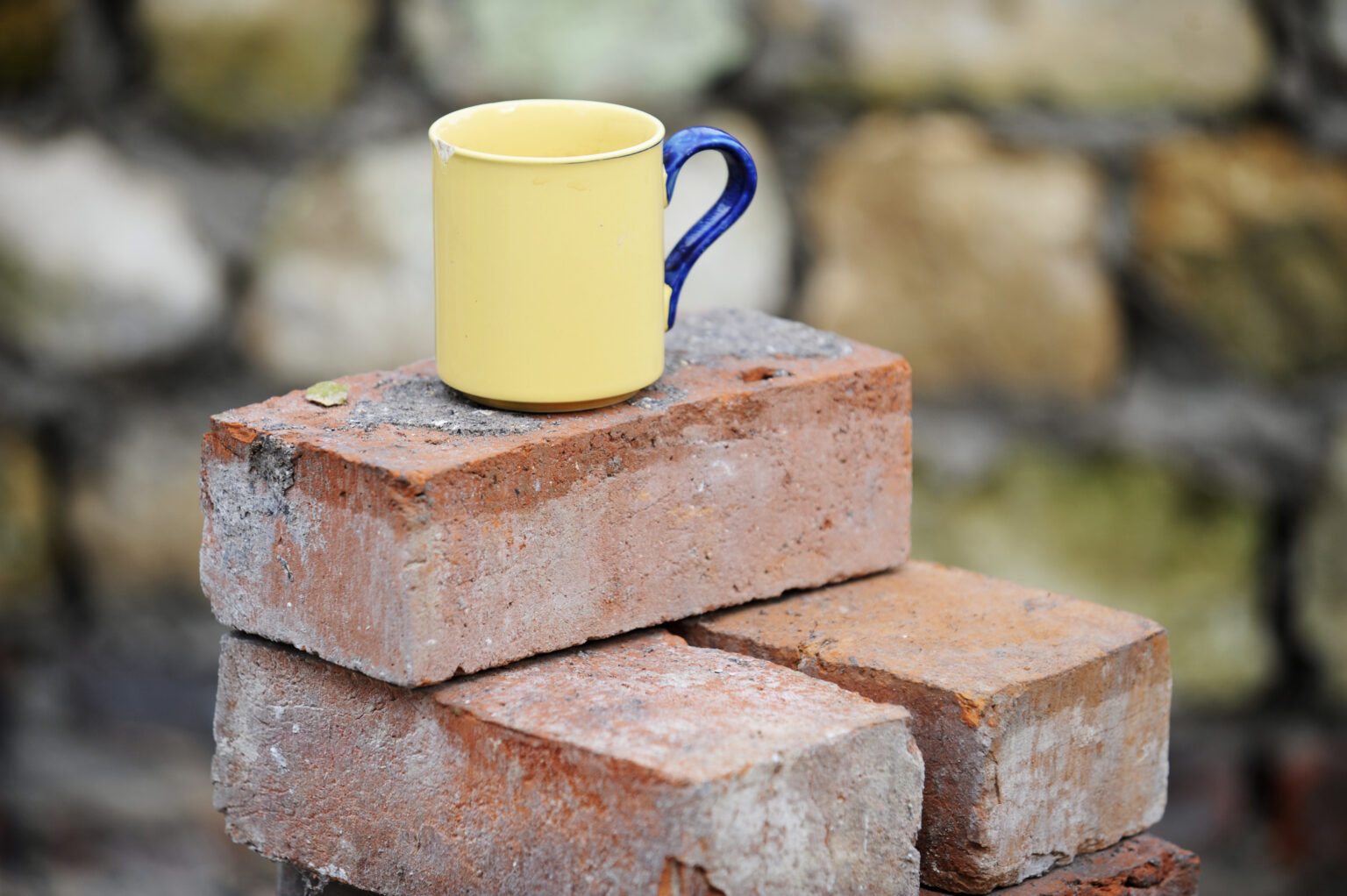 A builders mug of tea on a stack of reclaimed red bricks UK to represent laying the groundwork of business structure