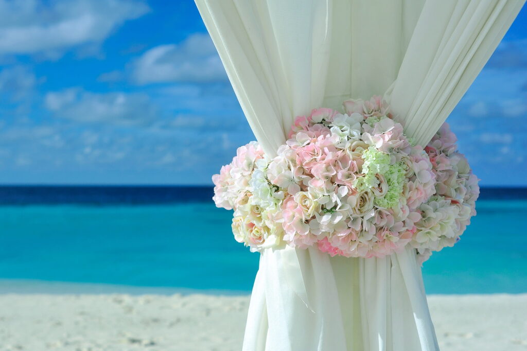 white cloth bound by roses and flowers in a wedding style at a beach